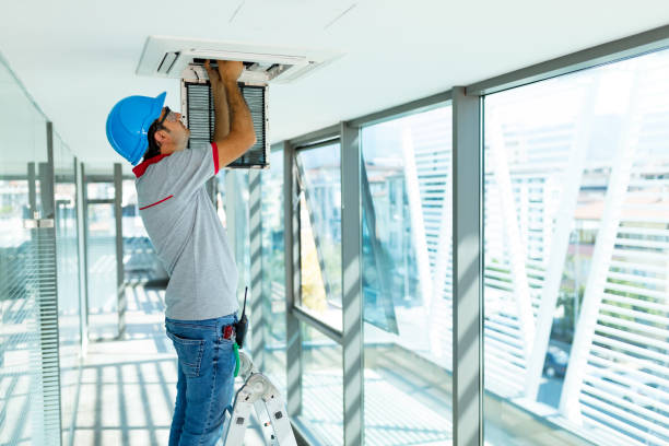 Worker installing air conditioner in building